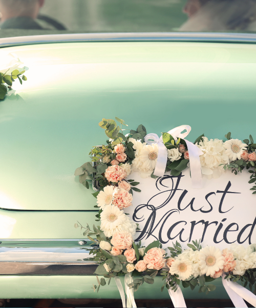 A wreath on the back of a car with just married written on it