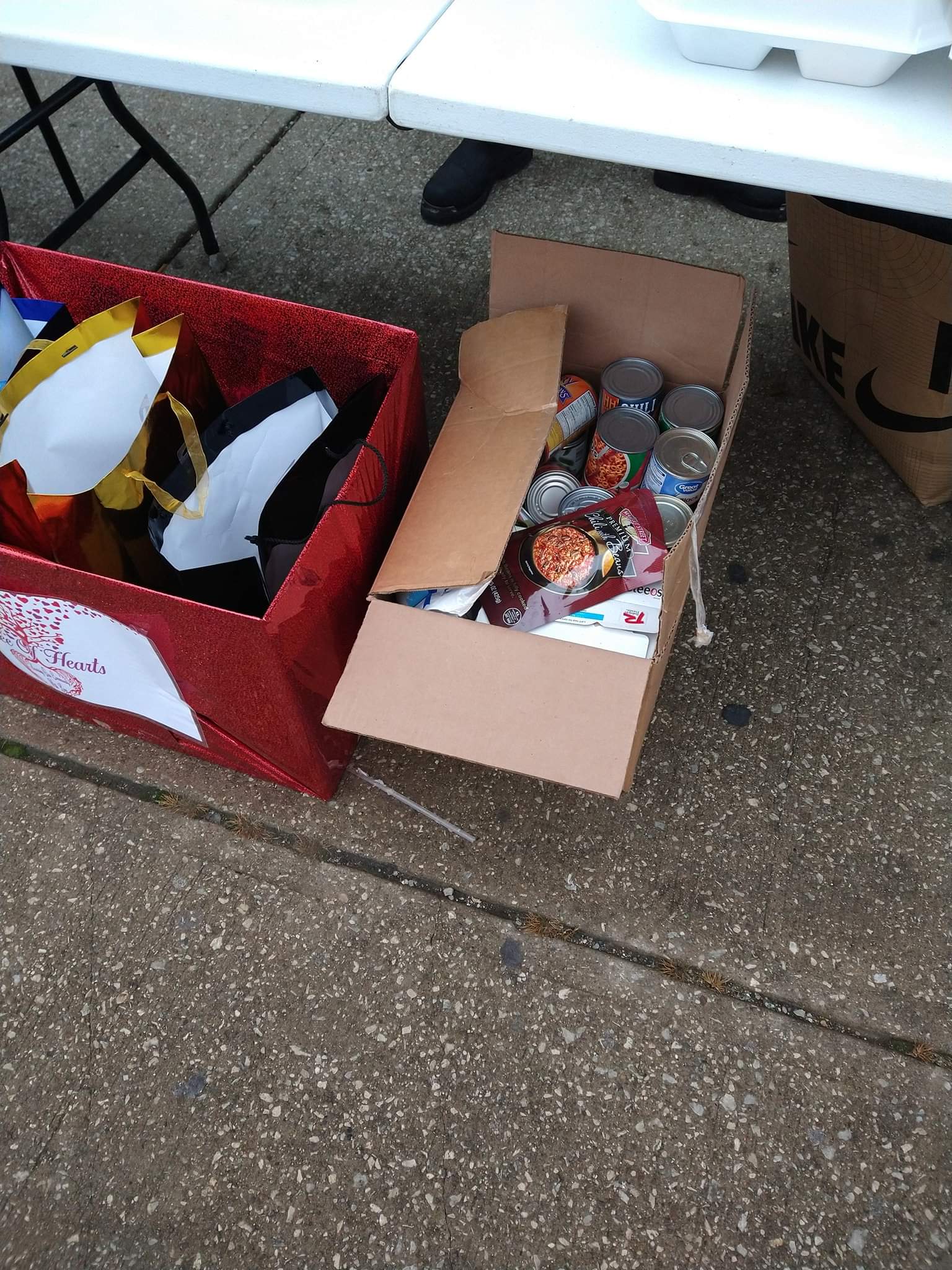 Two boxes of food sitting on the ground next to a table