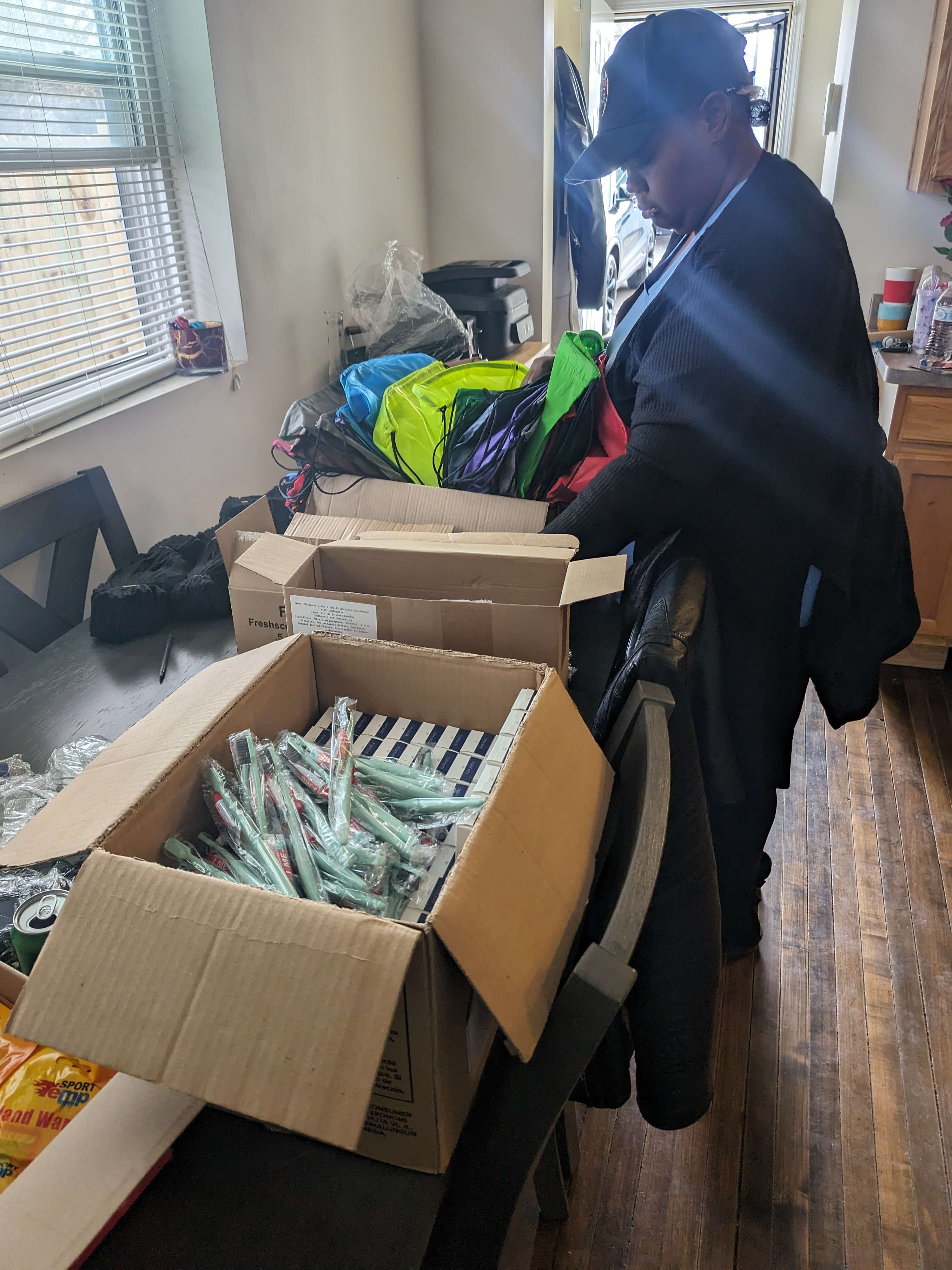 A man sitting on a chair in front of a box filled with clothes